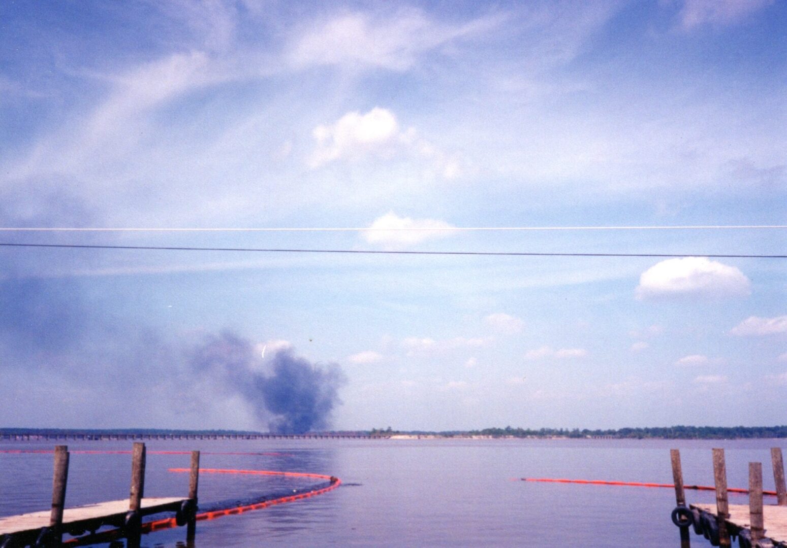 A fire burning in the water near a dock.